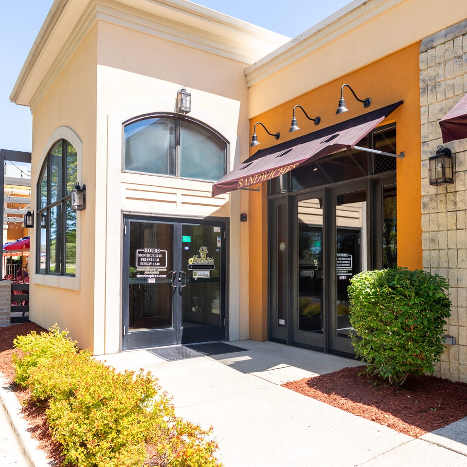 Exterior of Nonnie's restaurant with a "Sandwiches" awning and visible operating hours on the door.