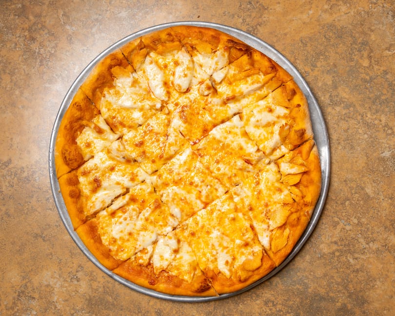 A freshly baked cheese pizza, cut into squares, on a metal pan.